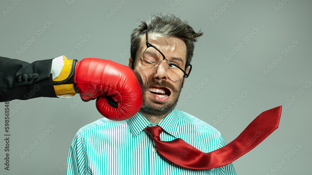 Mature man, businessman in red tie getting boxing punch in jaw from business competitors over grey background. Concept financial loses, business fall, deadlines, economic crisis - obrazy, fototapety, plakaty 