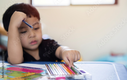 Preschool Asian boy with colored pencils on his desk. Concept of back to school.