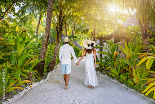Canvastavla A luxury couple in white summer clothing walks on a tropical island with lush gr