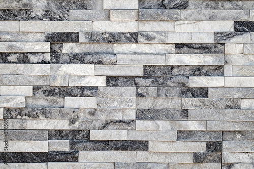 Wall background, lined with flat long granite tales of different shades of gray, uniform texture