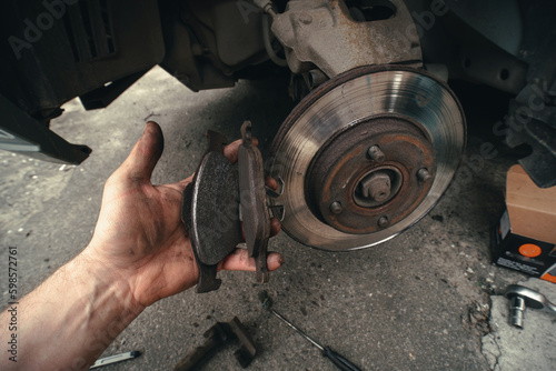 Disk brake and car service concept - Vehicle brake pad replacement service by hand of mechanic man in car, do it yourself, myself. Old and new pards.
