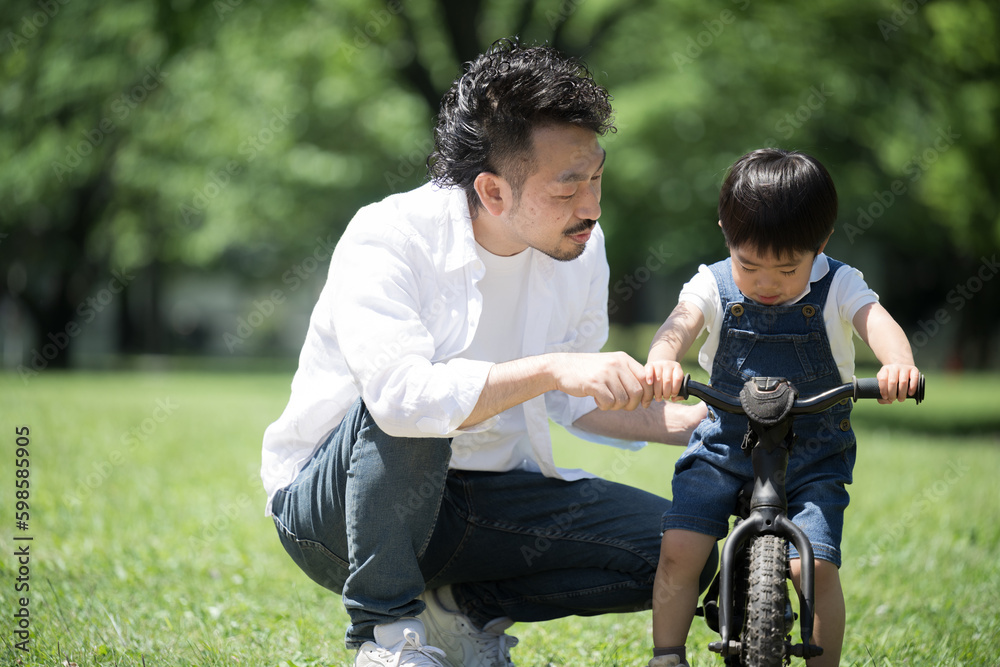Parent and child practicing bike riding Leisure in a fresh green park Mom and boy Copy space left Parent and child practicing bike riding Leisure in a fresh green park Mom and boy Copy space left