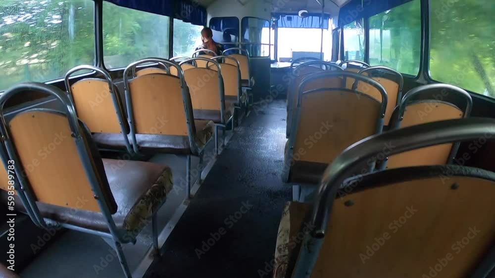 Man riding bus. Woman sitting on seat and riding inside empty old authentic public transport bus in city. Person on bus. POV. Wide angle. Transport travel moving. Soviet-style bus inside. Inside view
