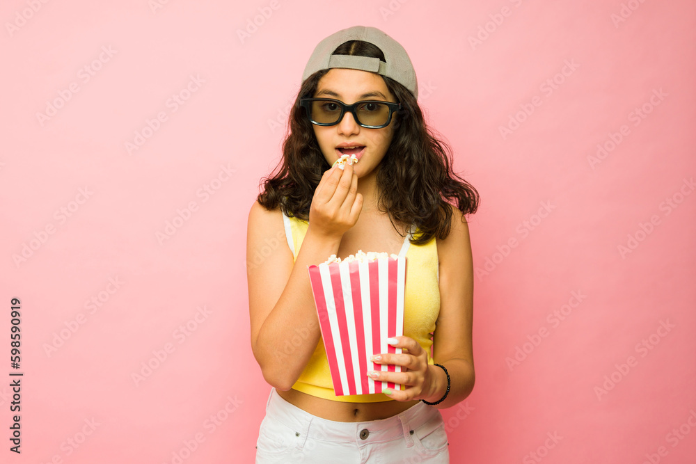 Adorable teen girl watching a 3d movie eating popcorn Adorable teen girl watching a 3d movie eating popcorn