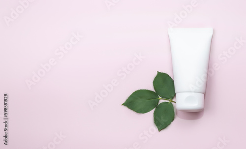 Flat lay composition with skin care products with green leaves on pink background. Copy space © Mariia