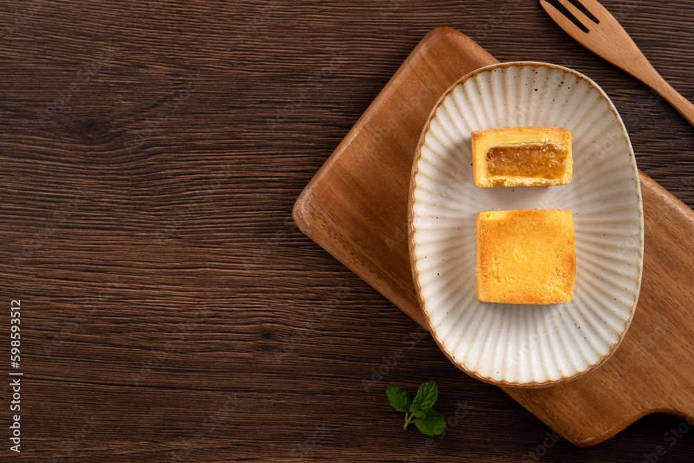 Delicious pineapple cake pastry in a plate on wooden table background with tea.