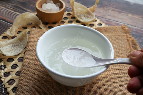 Edible Bird's nest soup with rock sugar in white bowl at close up view on wood table 