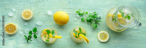 Lemonade with mint panorama. Lemon water drink with ice. Two glasses and a pitcher on a blue background, overhead flat lay shot. Detox beverage. Fresh homemade cocktail