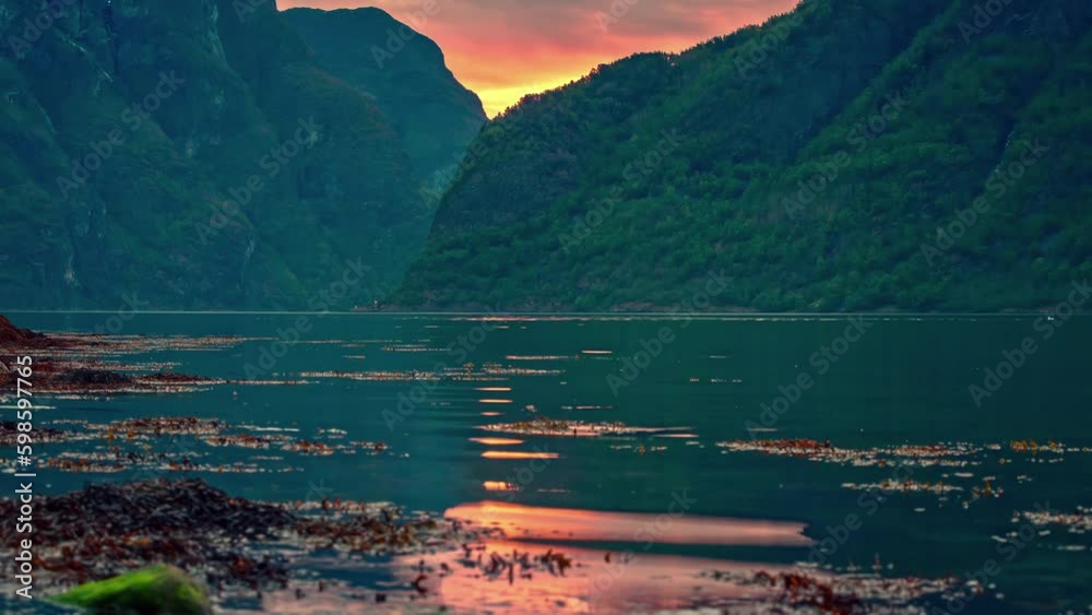 Yacht or cruiseship goes through waterway ocean between large green mountains, timelapse