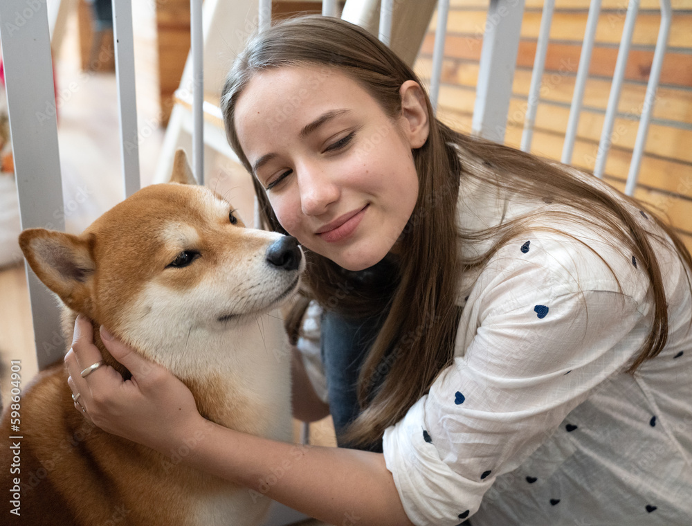 Beautiful girl have fun playing with her adorable pet friend at leisure. Friendly animal enjoying cuddle and play with owner who love and care. Young woman and her dog happy at home background.