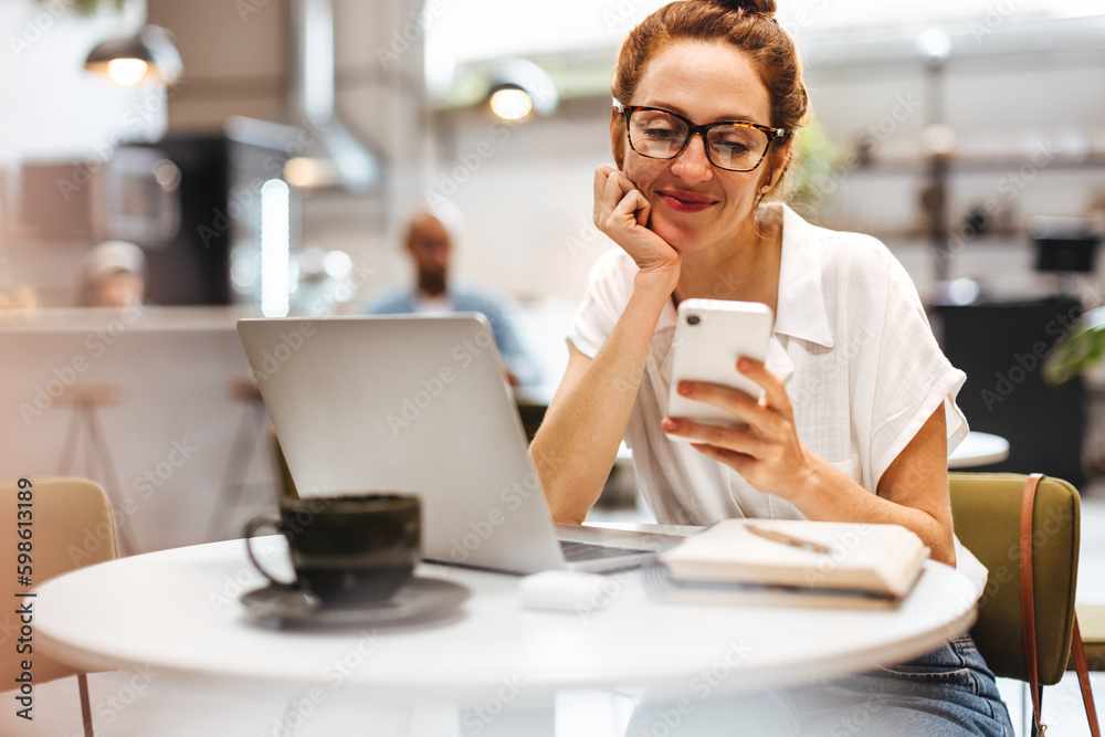 Caucasian woman taking a break from work to browse her phone in a cafe Caucasian woman taking a break from work to browse her phone in a cafe