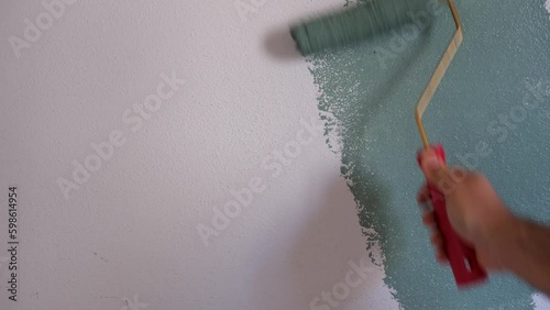 Man painting wall with green paint using roller. Construction worker, tool, apartment renovation. photo