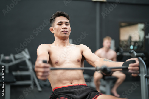 Young active athlete exercising on cross training equipment in fitness center or gym