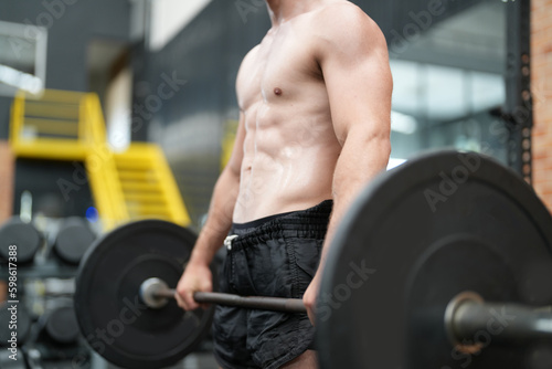 Young active athlete exercising on cross training equipment in fitness center or gym