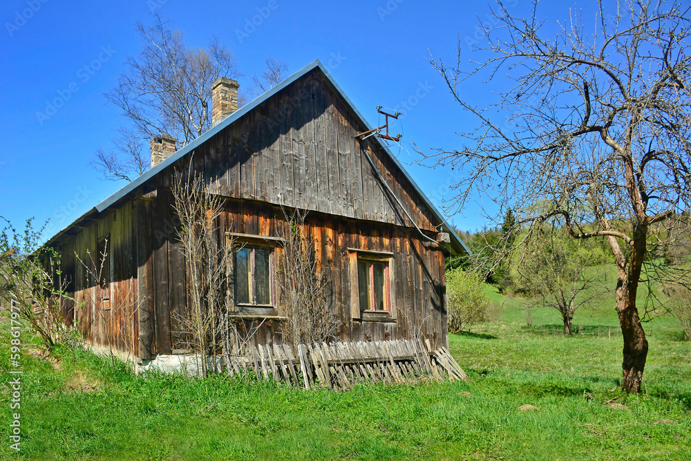 Old abandoned village buildings on a spring day on tree and blue sky background, rural landscape, Low Beskids, Poland Old abandoned village buildings on a spring day on tree and blue sky background, rural landscape, Low Beskids, Poland