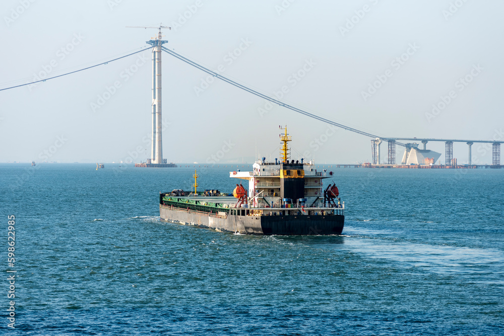 Cargo ship sailing toward the Hong Kong Zhuhai Macau (Macao) Bridge, near Chinese coast.