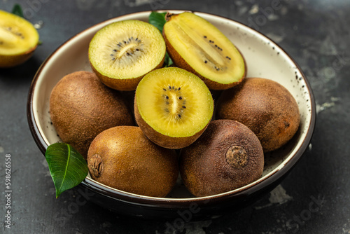 Whole and cut golden kiwifruit on a dark background  Healthy food concept. place for text  top view