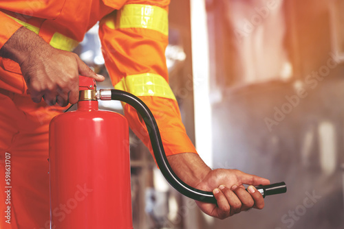 hand presses the trigger fire extinguisher available in fire emergencies conflagration damage background. Safety photo