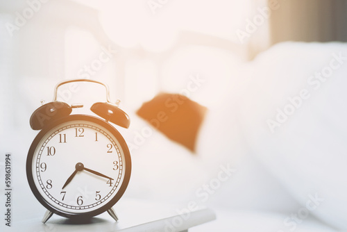 Close up of man lying in bed turning off hand reaching out for alarm clock color black Wake up late at morning at 7.20 am.