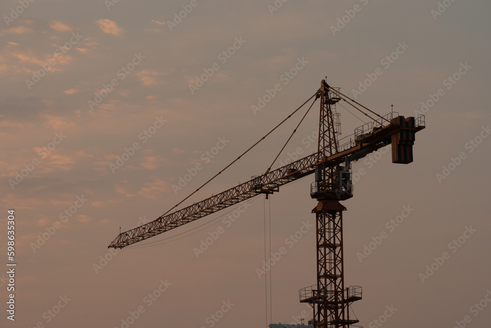 view of a lone tower crane at sunset