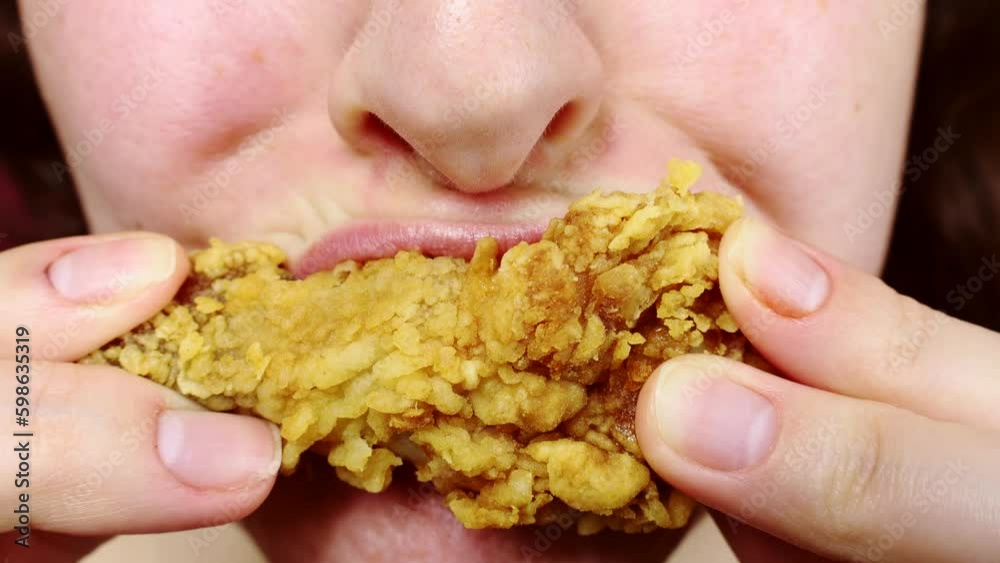 Woman eating a takeaway fried chicken wings from fast food cafe with a mouth and teeth close up Woman eating a takeaway fried chicken wings from fast food cafe with a mouth and teeth close up