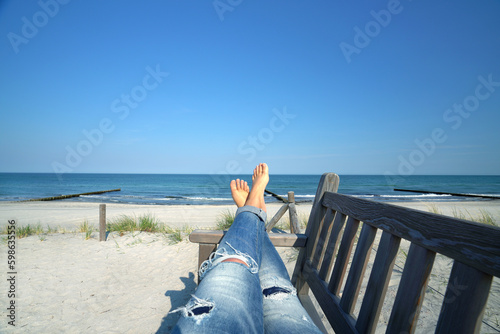 Fototapeta Naklejka Na Ścianę i Meble -  woman legs barefoot on a bench at the Baltic Sea with a view on sea