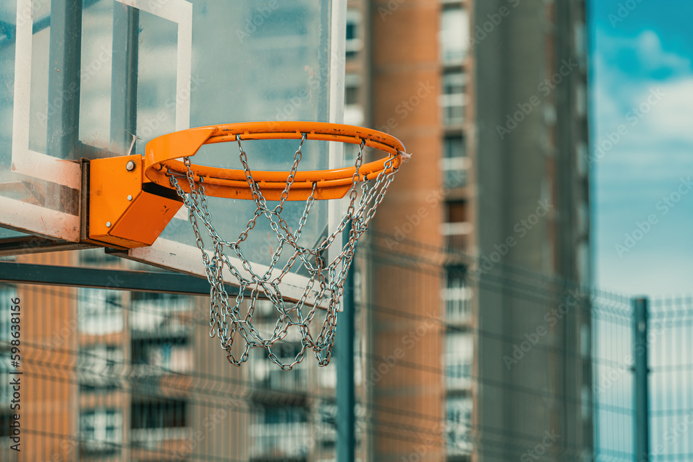Outdoor basketball backboard and hoop rim with chain net in urban residential district