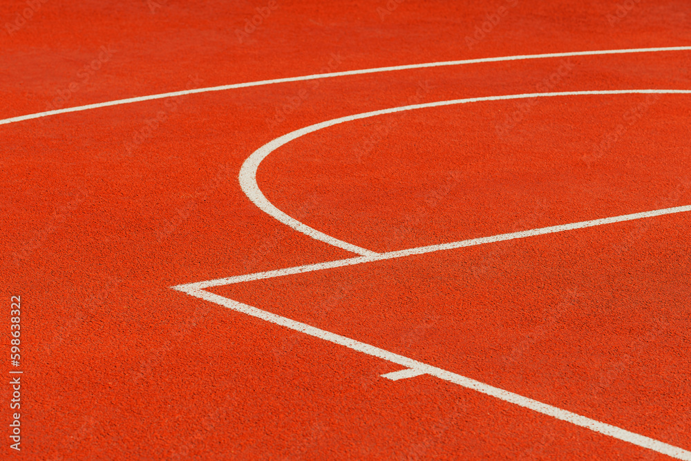 Minimalist abstract background of an orange tartan outdoor basketball court with white lines.