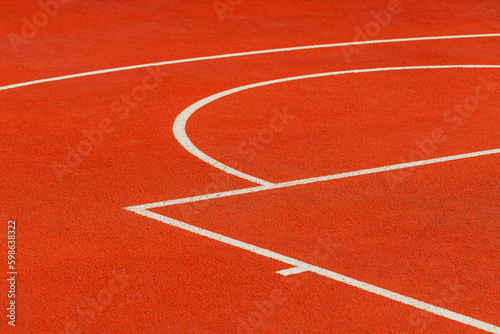 Minimalist abstract background of an orange tartan outdoor basketball court with white lines.