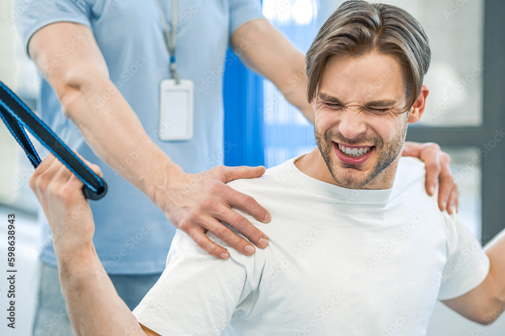 Young man having na physical therapy with instructor in the rehabilitation center Young man having na physical therapy with instructor in the rehabilitation center