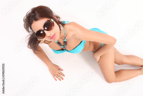 young woman in swimsuit and shorts on a white background