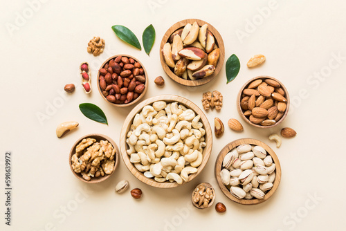 mixed nuts in wooden bowl. Mix of various nuts on colored background. pistachios, cashews, walnuts, hazelnuts, peanuts and brazil nuts