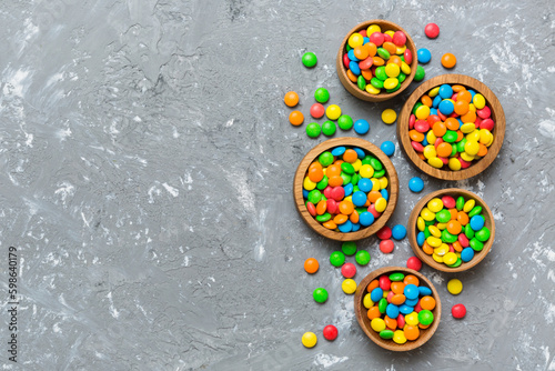 different colored round candy in bowl and jars. Top view of large variety sweets and candies with copy space