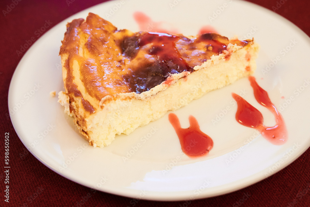 slice of cheesecake accompanied by strawberry jam on white plate slice of cheesecake accompanied by strawberry jam on white plate