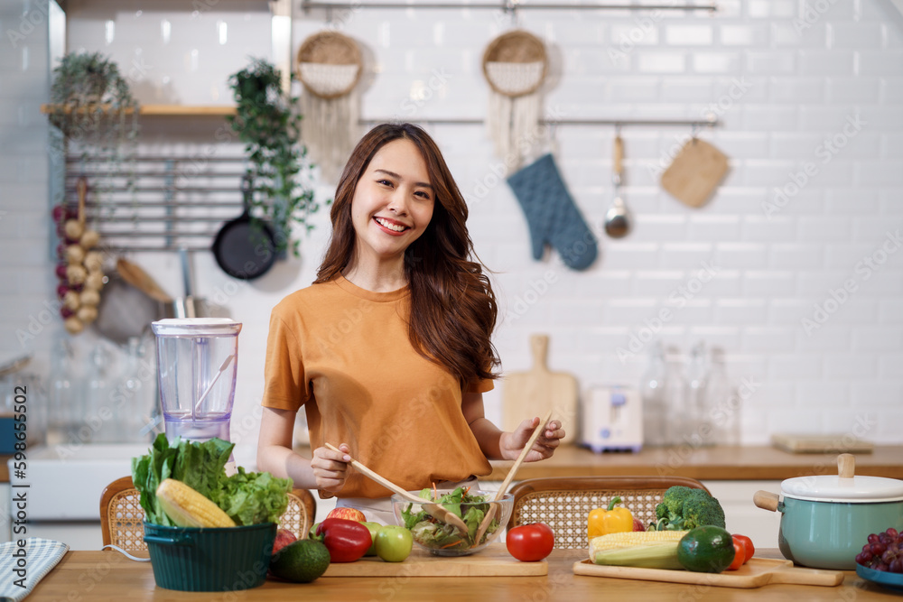Young Asian woman is preparing a fresh healthy vegan salad with many vegetables in the kitchen, Dieting Concept. Healthy food Lifestyle. Cooking At Home. Young Asian woman is preparing a fresh healthy vegan salad with many vegetables in the kitchen, Dieting Concept. Healthy food Lifestyle. Cooking At Home.