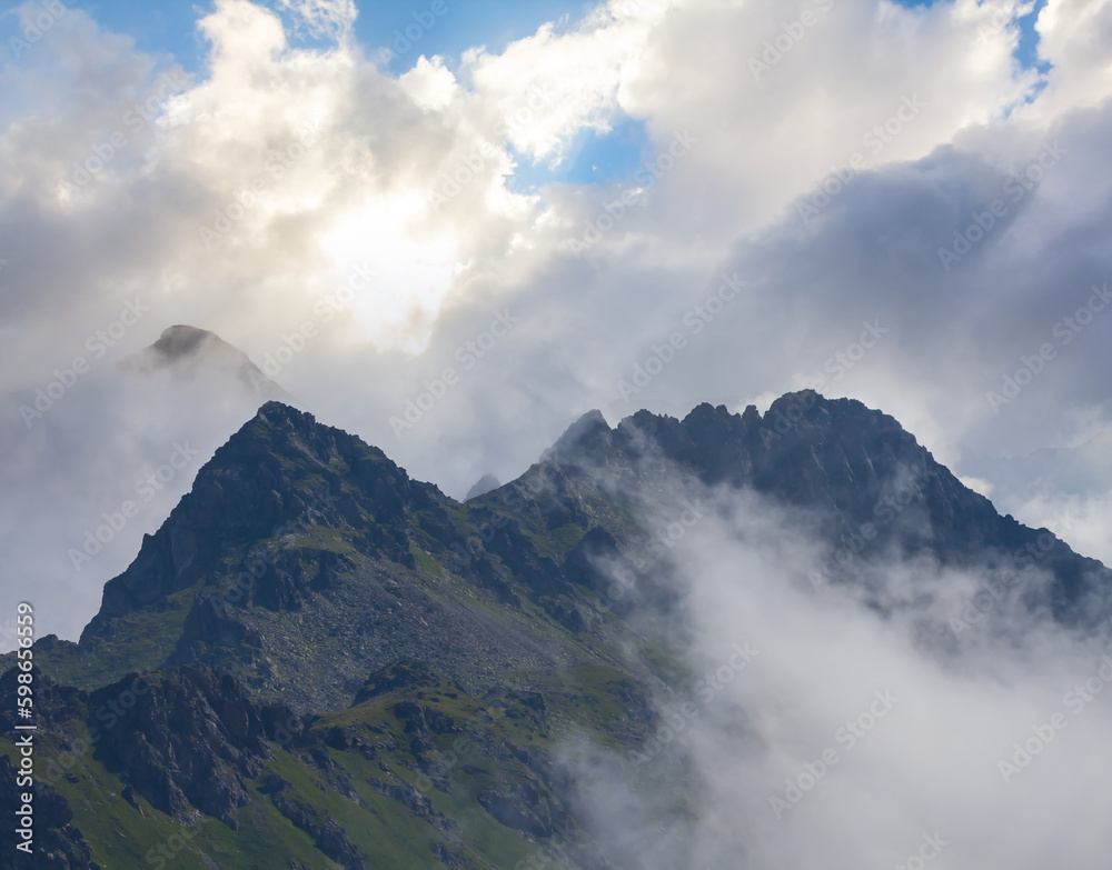 mountain ridge in dense clouds under a sparkle sun