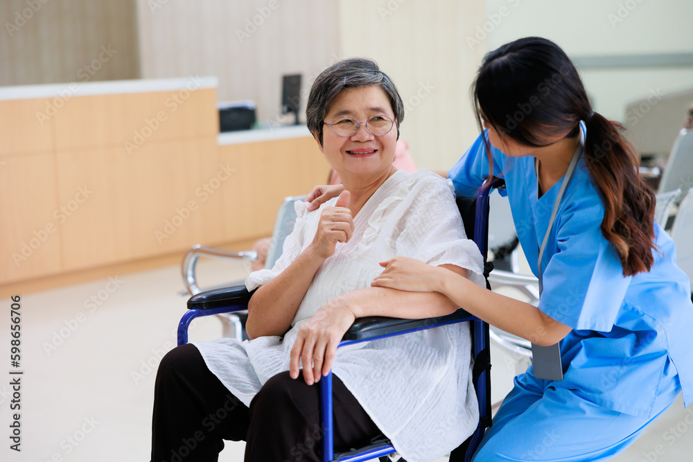 Obraz premium Young asian doctor in blue uniform and senior woman holding hands together. Positive Asian woman caregiver helping patient.