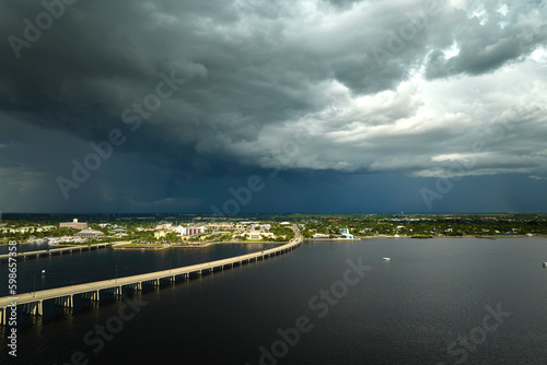 Heavy thunderstorm approaching traffic bridge connecting Punta Gorda and Port Charlotte over Peace River. Bad weather conditions for driving during rainy season in Florida