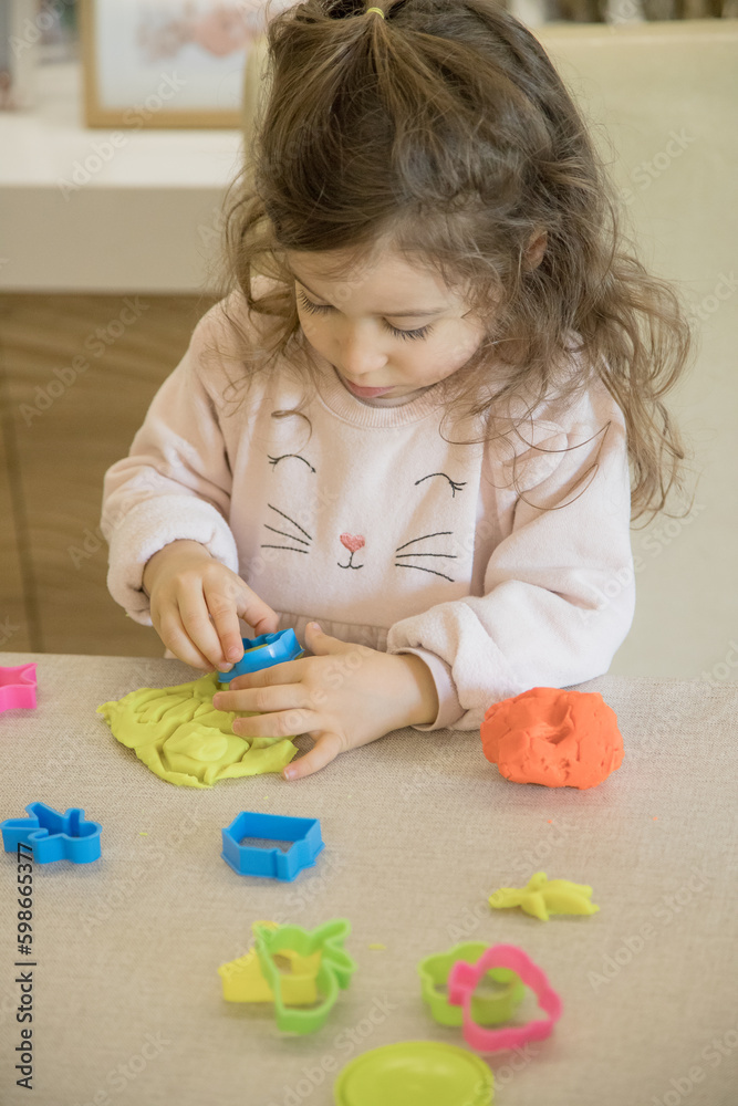 Caucasian child, two or three years old, playing and exercising fine motor skills with her hands, with clay and colored plasticine. Concept of happy childhood, learning and creativity. Copy space Caucasian child, two or three years old, playing and exercising fine motor skills with her hands, with clay and colored plasticine. Concept of happy childhood, learning and creativity. Copy space