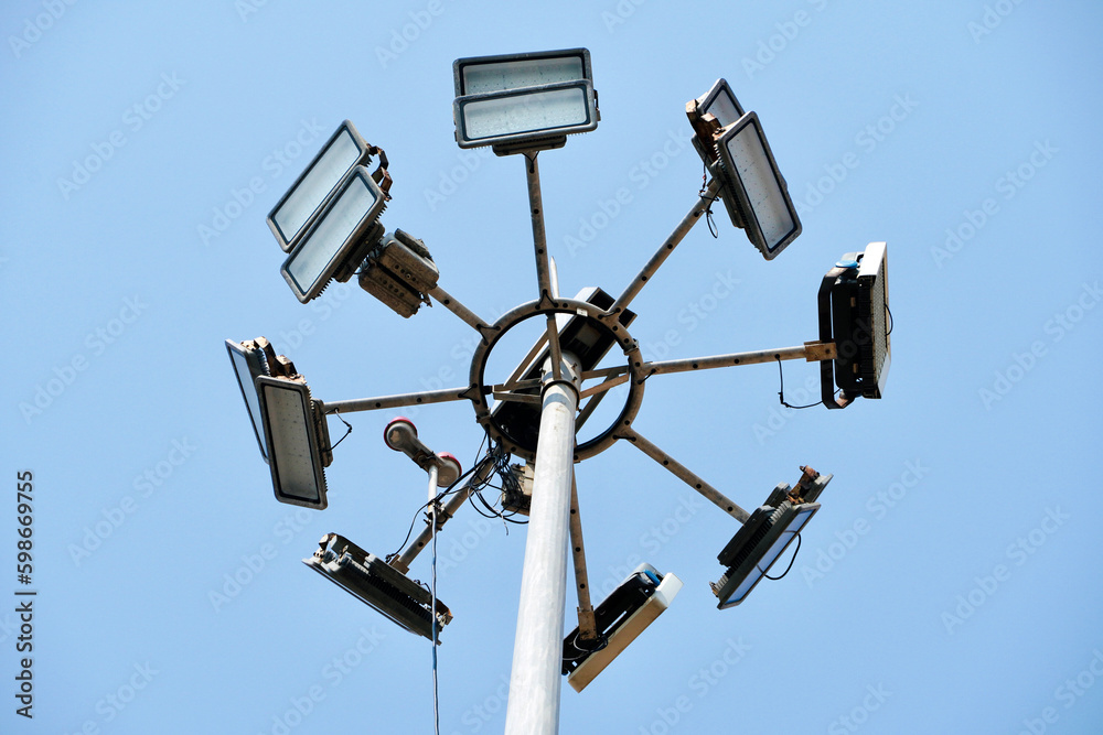 High mast lighting pole lights. Round sport light with blue cloud sky background. High mast lighting pole lights. Round sport light with blue cloud sky background.