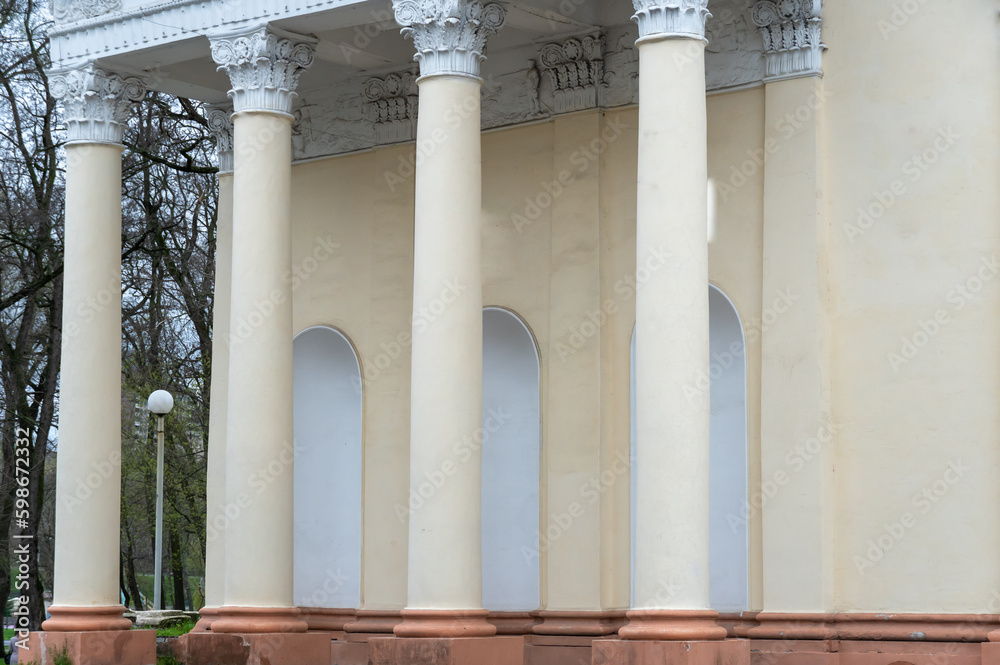 Architectural columns with figures and white stucco wealth. Solemn entrance to city park is made in style of stalin's empire. Propylaea richly decorated with symbols of soviet era. Plaster historical. Architectural columns with figures and white stucco wealth. Solemn entrance to city park is made in style of stalin's empire. Propylaea richly decorated with symbols of soviet era. Plaster historical.