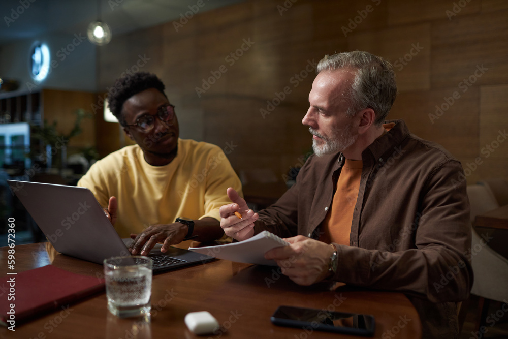 Colleagues planning work together using laptop while having business meeting in cafe