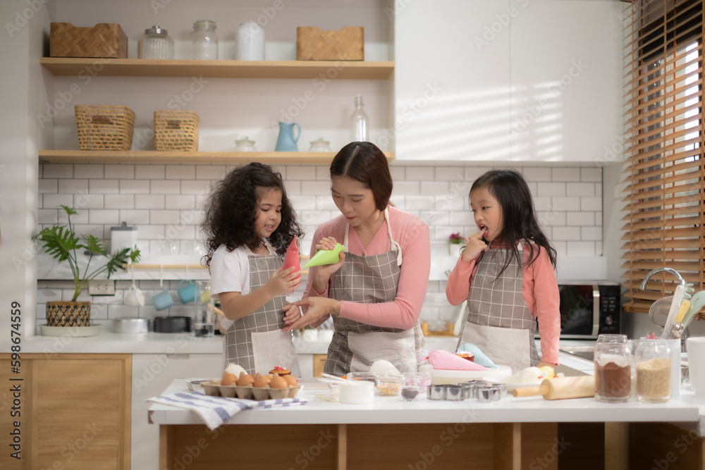 Mom and two daughter enjoy with cooking together in kitchen on mother's day to make some cake for celebration.0 Mom and two daughter enjoy with cooking together in kitchen on mother's day to make some cake for celebration.0