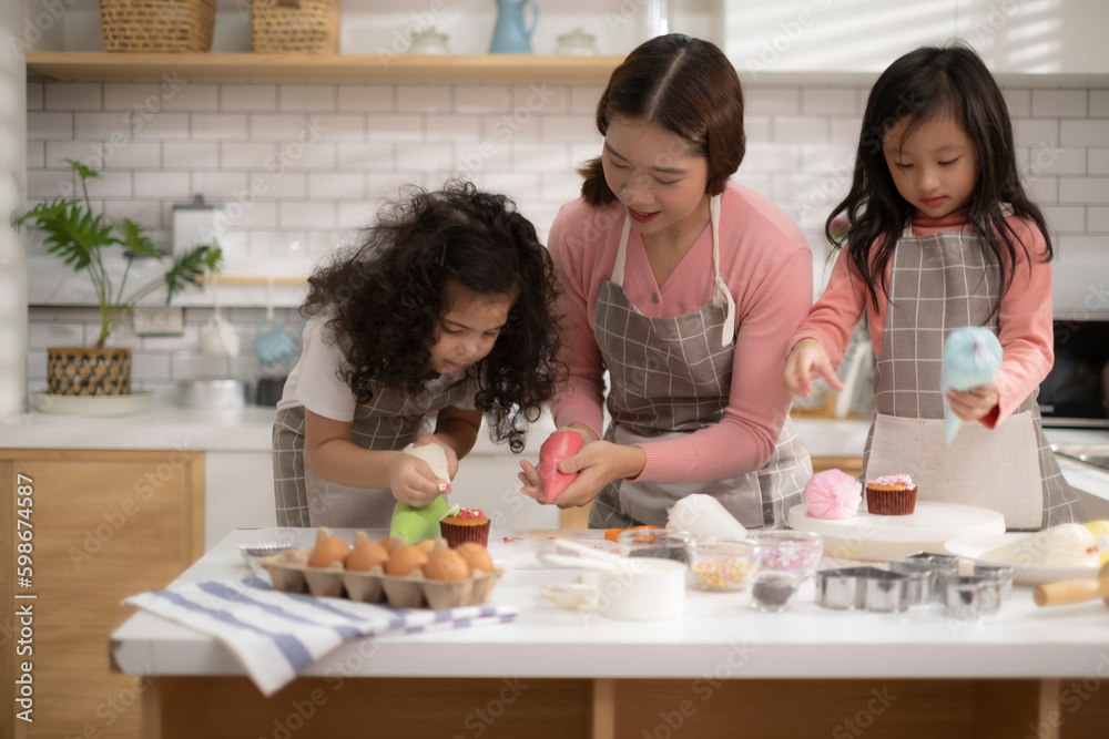 Asian mom teach her mixed race daughter decorating cup cake, kids enjoy with helping her mum do celabration cake in mother's day.