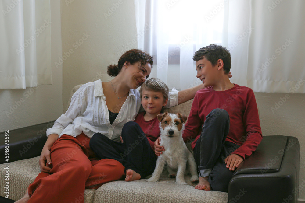 Adult woman enjoying weekend at home and spending quality time with her two sons and a jack russell terrier pup. Close up, copy space, background.