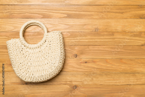 Straw bag on wooden background, top view