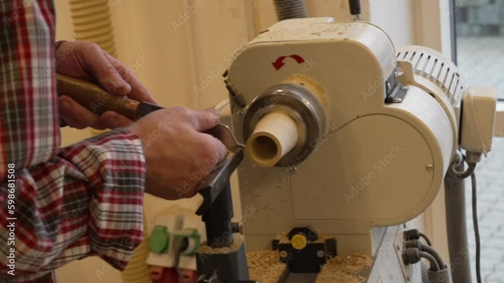 Man carpenter using chisel for shaping piece of wood on turning lathe machine with many shavings at workshop - close up. Carpentry, hobby, craftsmanship and woodworking concept Man carpenter using chisel for shaping piece of wood on turning lathe machine with many shavings at workshop - close up. Carpentry, hobby, craftsmanship and woodworking concept