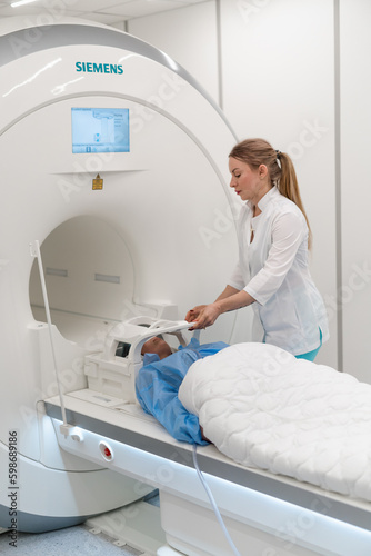 a radiologist in a medical clinic puts the device on the patient's head before the brain magnetic resonance imaging procedure