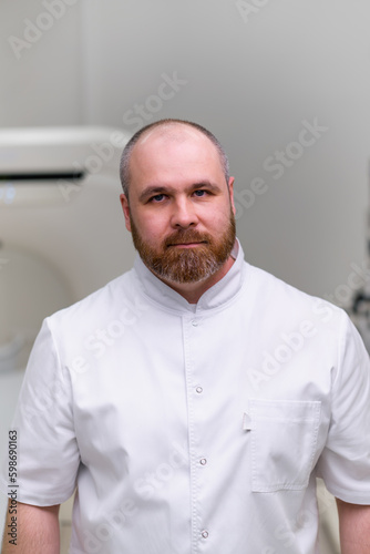 serious bearded doctor CT radiologist in computed tomography office waiting for patients before starting work