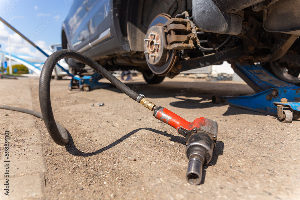 Car on tire mounting with removed wheel on pneumatic jack, seasonal tire change, car service concept. Car on tire mounting with removed wheel on pneumatic jack, seasonal tire change, car service concept.